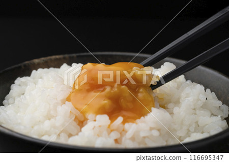 Raw egg on rice: Pick up the rice with chopsticks and crush the yolk with chopsticks Raw egg on rice: Pick up the rice with chopsticks and crush the yolk with chopsticks 116695347