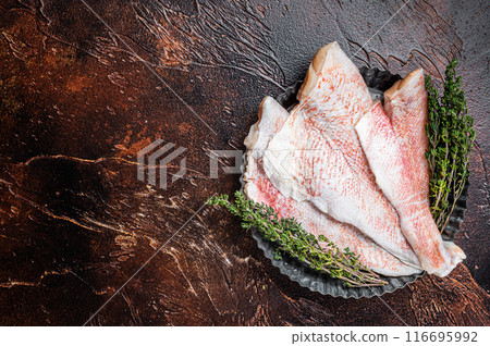 Raw ocean red perch fillet, Snapper fish with herbs. Dark background. Top view. Copy space Raw ocean red perch fillet, Snapper fish with herbs. Dark background. Top view. Copy space 116695992