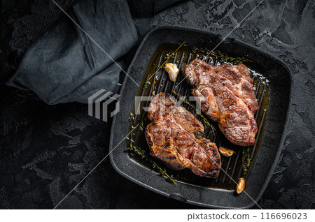 Grilled Pork steaks, neck meat on grill pan. Black background. Top view Grilled Pork steaks, neck meat on grill pan. Black background. Top view 116696023