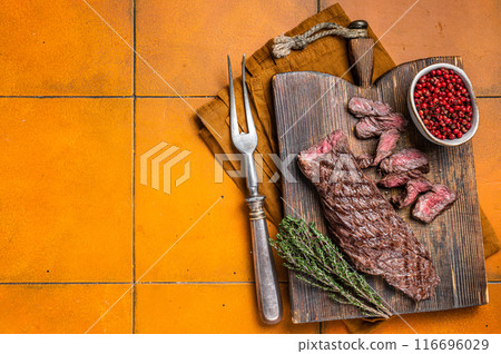 Grilled Medium Rare Machete or skirt beef meat steak on wooden cutting board. Orange background. Top view. Copy space Grilled Medium Rare Machete or skirt beef meat steak on wooden cutting board. Orange background. Top view. Copy space 116696029