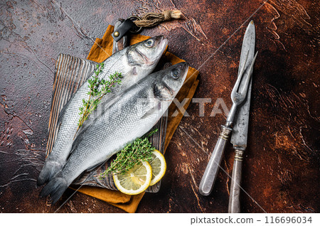 Raw Sea Bass, Branzino fish with thyme and lemon. Dark background. Top view Raw Sea Bass, Branzino fish with thyme and lemon. Dark background. Top view 116696034