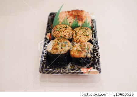 A black tray of sushi with decorative gold lines contains four pieces of seared nigiri sushi 116696526