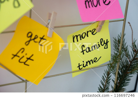 MORE FAMILY TIME goal on Vision board with new year resolutions aims on sticky notes. Preparation for New Year. Planning and setting goals for personal development  116697246