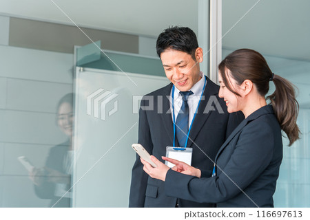 Businesswoman and businessman with smartphones in the office (IT company/company employee) 116697613