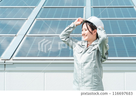An engineer/business person in work clothes from an electric power company/electrical contractor standing in front of a solar power generation/solar panel An engineer/business person in work clothes from an electric power company/electrical contractor standing in front of a solar power generation/solar panel 116697683