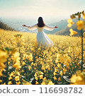 A woman standing backwards in a refreshing rapeseed flower field on a sunny day 116698782