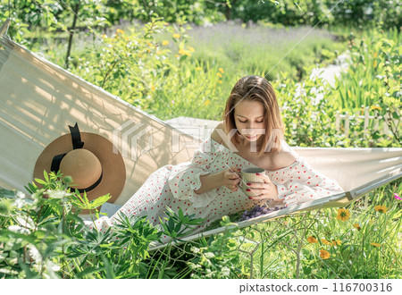 Young woman relaxing in a hammock outdoors Young woman relaxing in a hammock outdoors 116700316