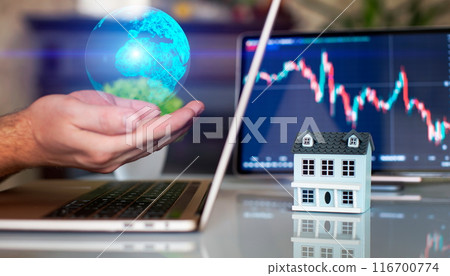 A businessman is using a laptop computer and holding a halogram on the ground with a choice of where to buy a house, with a stock market chart on the screen 116700774
