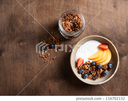 Delicious natural yogurt with homemade granola, peach and berries in a bowl  116702132