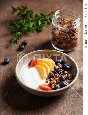 Fresh natural yogurt with homemade muesli; peach; strawberry and blueberry in a bowl Fresh natural yogurt with homemade muesli; peach; strawberry and blueberry in a bowl 116702143
