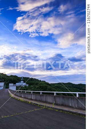 Evening view of Nunome Dam in the summer of 2024: The evening sky above the dam shows a gradation from indigo to gold ② 116702744