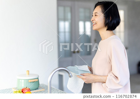 Middle-aged woman wiping dishes Middle-aged woman wiping dishes 116702874