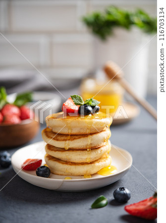 Homemade classic American pancakes in a stack with fresh berries and honey close-up  116703134