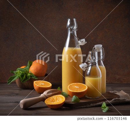 freshly squeezed orange juice in three bottles with citrus fruits on cutting board and  116703146