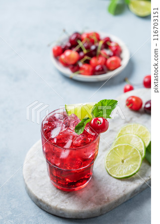 Cherry-lime mojito cocktail with mint, lime and ice on a marble board on a light background. Cherry-lime mojito cocktail with mint, lime and ice on a marble board on a light background. 116703151