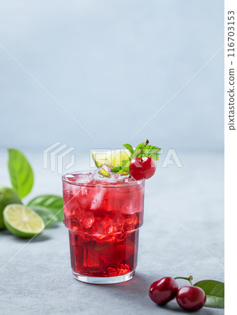 Cherry-lime mojito cocktail with mint, lime and ice on a blue background with fresh berries. Cherry-lime mojito cocktail with mint, lime and ice on a blue background with fresh berries. 116703153