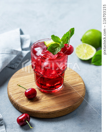 Cherry-lime mojito cocktail with mint, lime and ice on a wooden board on a blue background 116703155