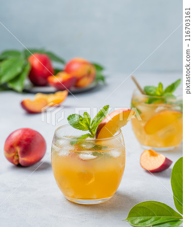 Two glasses with peach cocktail, lemonade or iced tea on a light background. 116703161