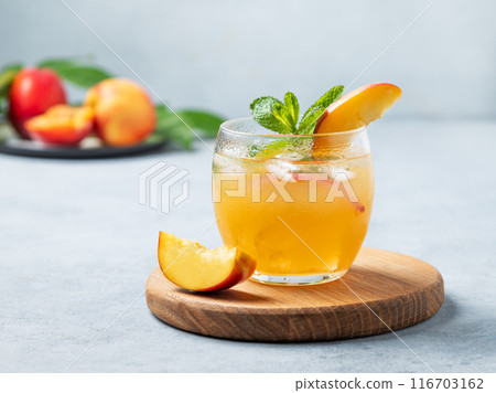 Refreshing peach cocktail, lemonade or iced tea on a wooden board on a light background. 116703162