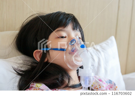 Sick little asian girl inhalation with nebulizer for respiratory treatment 116703602