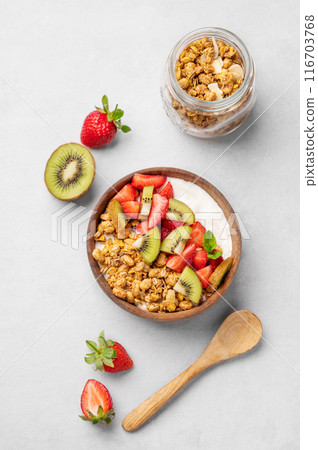 Natural yogurt with granola, kiwi and strawberries in a wooden bowl on a light background Natural yogurt with granola, kiwi and strawberries in a wooden bowl on a light background 116703768