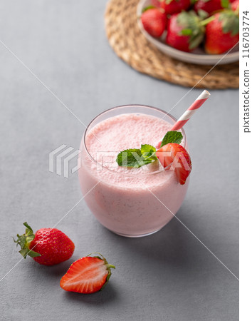 A glass of fresh strawberry smoothie with mint on a blue background with fresh berries. A glass of fresh strawberry smoothie with mint on a blue background with fresh berries. 116703774