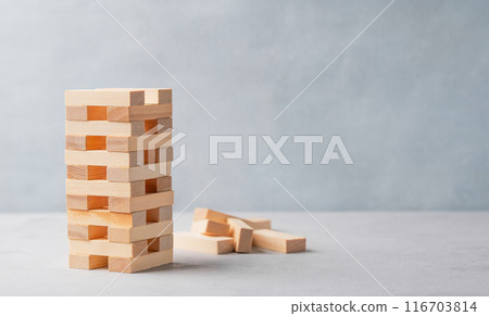 Wooden game tower on a light background with several pulled out blocks. 116703814