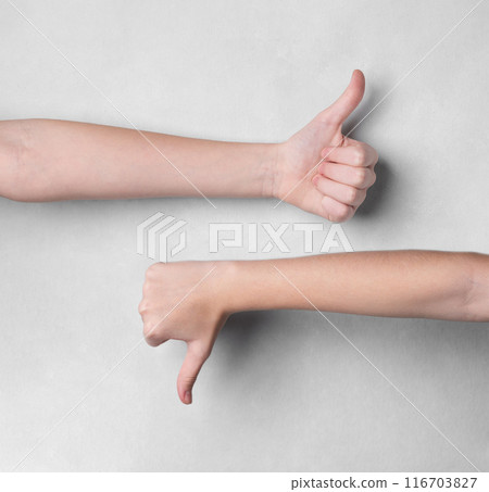 Two hands showing thumbs up and thumbs down gestures on a light background. Two hands showing thumbs up and thumbs down gestures on a light background. 116703827
