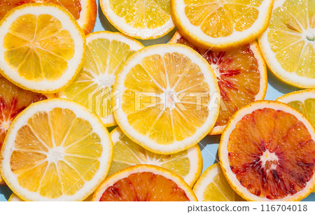 Slices of lemons and blood oranges close up on a blue background. Slices of lemons and blood oranges close up on a blue background. 116704018