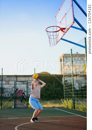 caucasian little basketball player jumps to throw the ball into the basket hoop 116704181