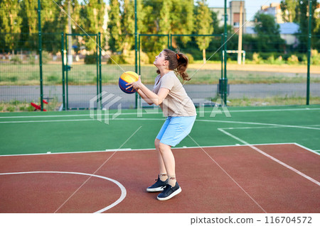 caucasian little basketball player jumps to throw the ball into the basket hoop 116704572