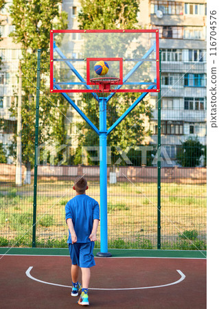 caucasian little basketball player jumps to throw the ball into the basket hoop 116704576