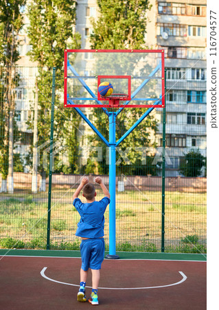 caucasian little basketball player jumps to throw the ball into the basket hoop caucasian little basketball player jumps to throw the ball into the basket hoop 116704577