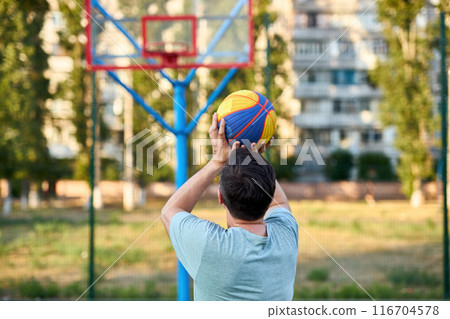 Middle aged man playing basketball on city court 116704578