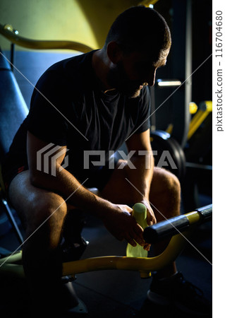 man sitting in a dark gym resting after exercises 116704680