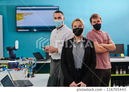 A group of colleagues stand ingin a robotics laboratory, arms crossed, wearing protective masks, symbolizing their teamwork and commitment to technological innovation and scientific research. A group of colleagues stand ingin a robotics laboratory, arms crossed, wearing protective masks, symbolizing their teamwork and commitment to technological innovation and scientific research. 116705443