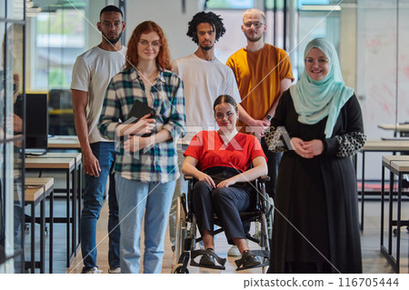 A diverse group of young business people congregates within a modern startup's glass-enclosed office, featuring inclusivity with a person in a wheelchair, an African American young man , and a hijab 116705444