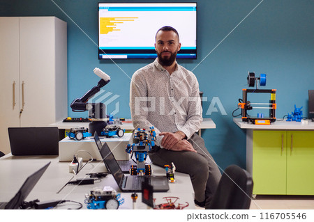 A bearded man in a modern robotics laboratory, immersed in research and surrounded by advanced technology and equipment. A bearded man in a modern robotics laboratory, immersed in research and surrounded by advanced technology and equipment. 116705546