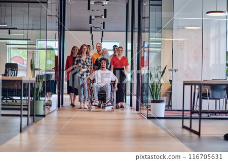 A diverse group of young business people congregates within a modern startup's glass-enclosed office, featuring inclusivity with a person in a wheelchair, an African American young man , and a hijab A diverse group of young business people congregates within a modern startup's glass-enclosed office, featuring inclusivity with a person in a wheelchair, an African American young man , and a hijab 116705631