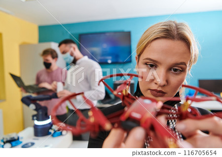 A group of students working together in a laboratory, dedicated to exploring the aerodynamic capabilities of a drone 116705654