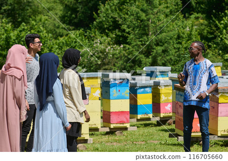 A diverse group of young friends and entrepreneurs explore small honey production businesses in the natural setting of the countryside. 116705660