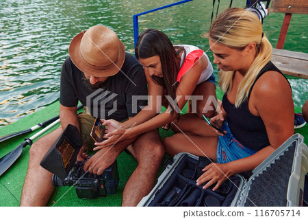 A professional cameraman showing the footage to a group of womans that they just shot A professional cameraman showing the footage to a group of womans that they just shot 116705714
