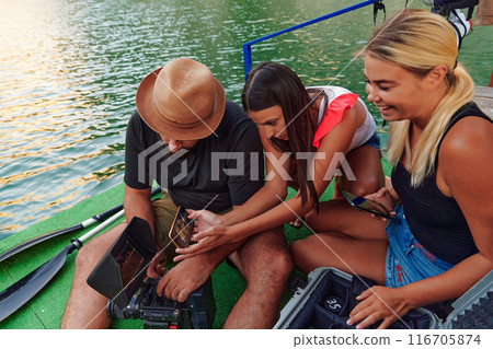 A professional cameraman showing the footage to a group of womans that they just shot A professional cameraman showing the footage to a group of womans that they just shot 116705874