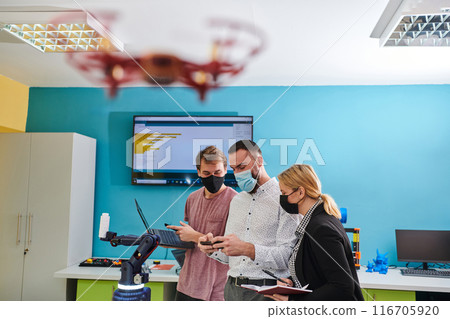 A group of students working together in a laboratory, dedicated to exploring the aerodynamic capabilities of a drone 116705920
