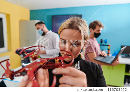 A group of students working together in a laboratory, dedicated to exploring the aerodynamic capabilities of a drone A group of students working together in a laboratory, dedicated to exploring the aerodynamic capabilities of a drone 116705952