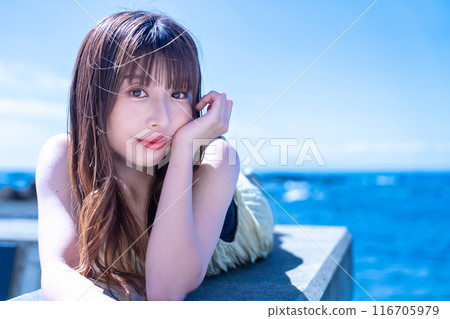 一位年輕女子躺在防波堤上享受大海 116705979