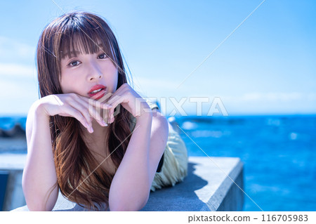 A young woman lying on a breakwater and enjoying the sea A young woman lying on a breakwater and enjoying the sea 116705983