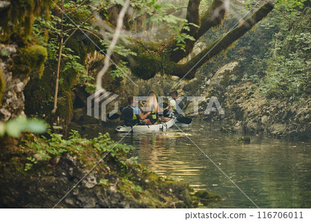 A group of friends enjoying having fun and kayaking while exploring the calm river, surrounding forest and large natural river canyons 116706011