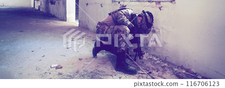 A professional soldier carries out a dangerous military mission in an abandoned building 116706123