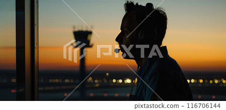 Silhouette of a skilled air traffic controller managing flights in a control tower. 116706144
